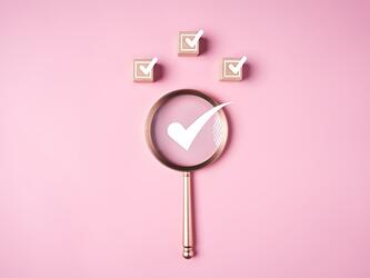 magnifying glass on a pink background with white ticks
